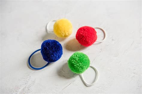 tube of galore|4 colourful pom pom hair bobble elastics in a tube .